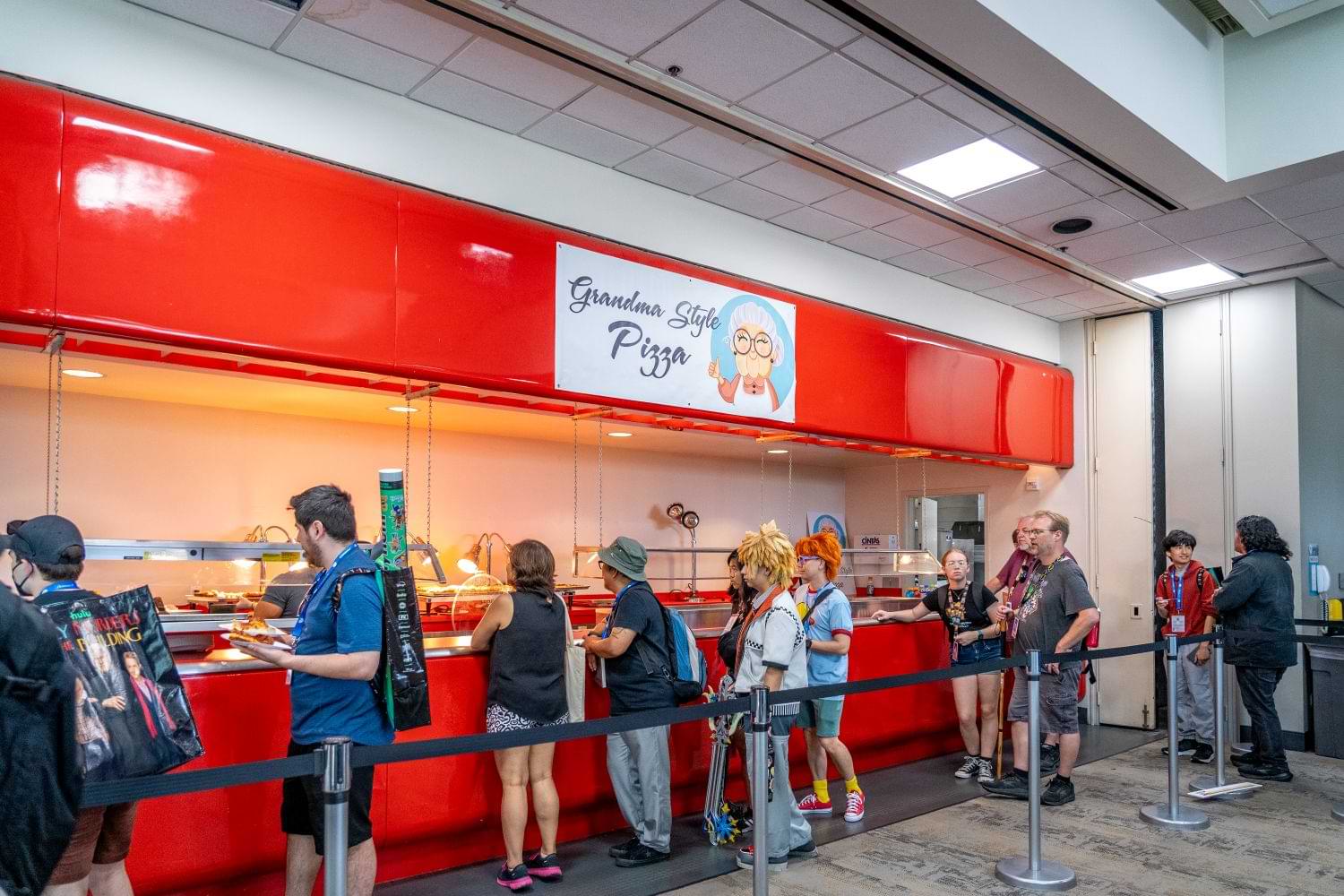 Comic-Con attendees in line for pizza at a stand that says “Grandma Style Pizza”